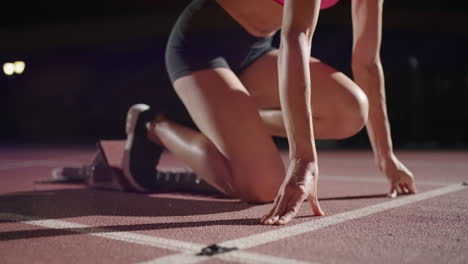 Mujer-Con-La-Mano-En-La-Pista-Mientras-Se-Agacha-En-La-Posición-Inicial-Al-Comienzo-De-Una-Carrera.-La-Atleta-Femenina-Se-Prepara-Y-Comienza.-Manos-Del-Corredor-Esperando-Al-Inicio-Frente-A-La-Línea-De-Inicio-En-El-Suelo.